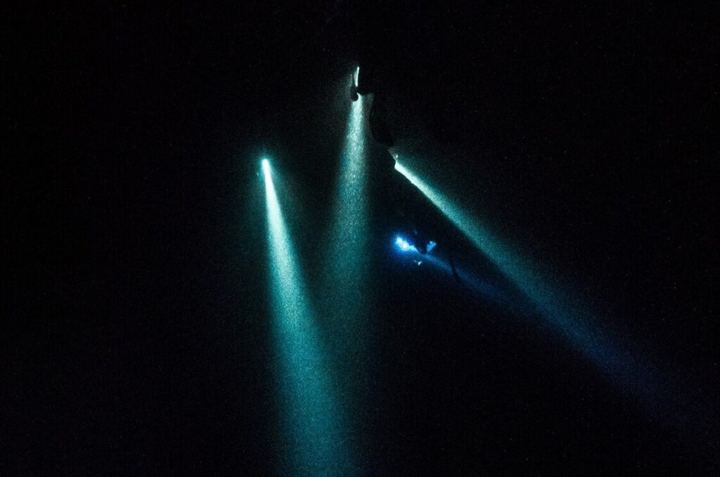 Linternas de buceadores en la oscuridad durante un buceo nocturno