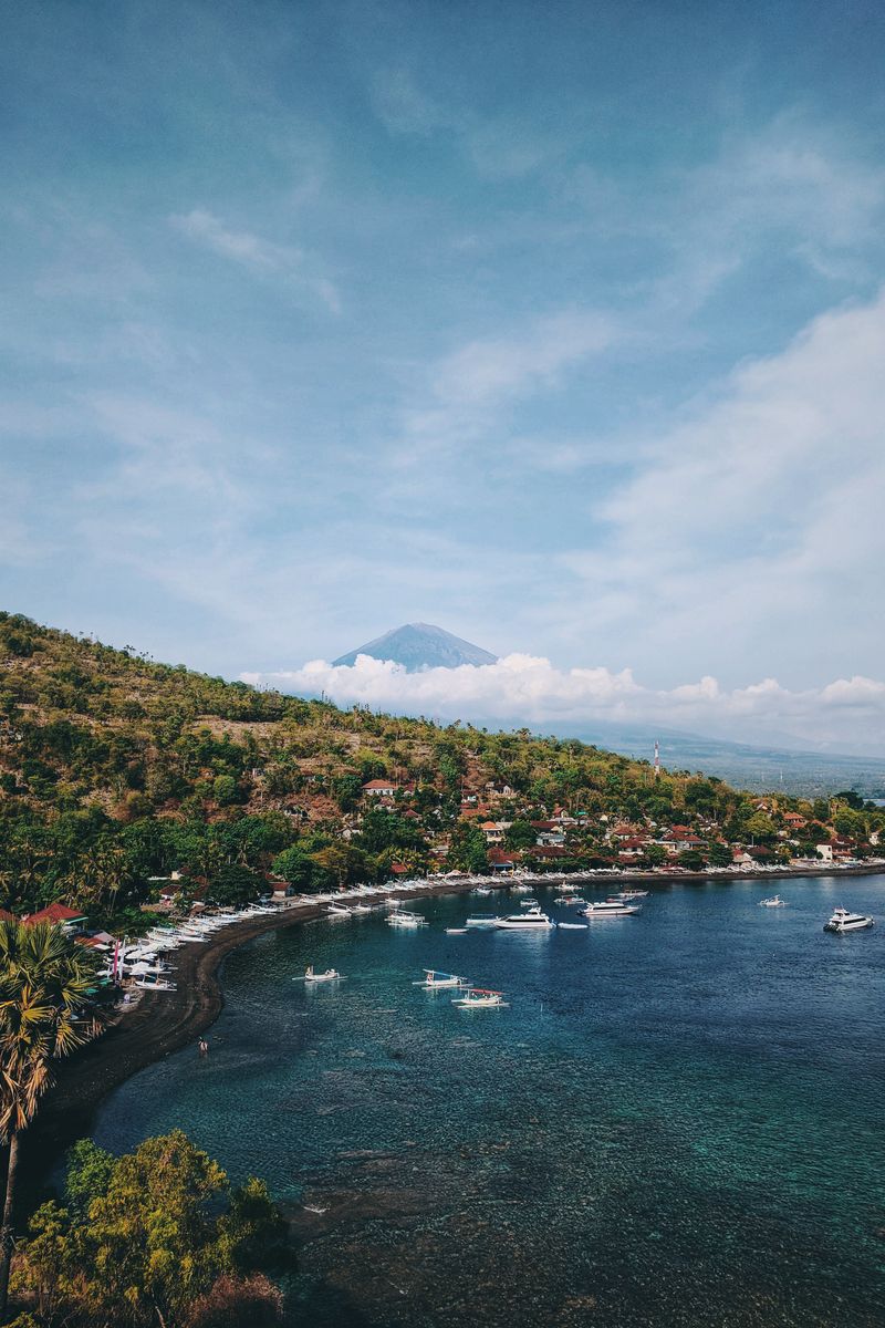 A tranquil coastal scene in Bali featuring Mount Agung, lush greenery, and turquoise waters.