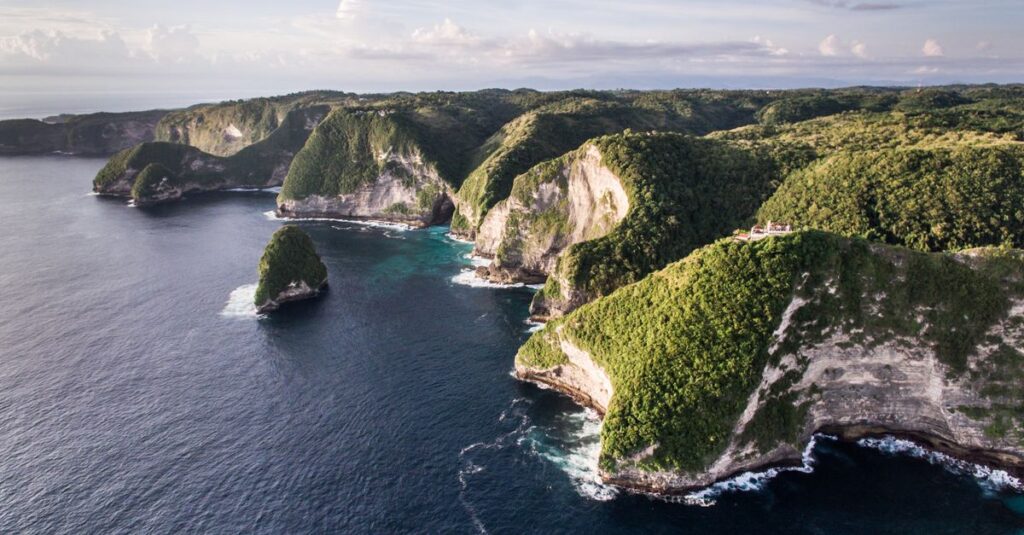 Drone shot of lush green cliffs and turquoise ocean at Nusa Penida in Bali, Indonesia.