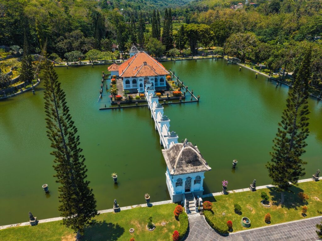 Aerial shot of a traditional water palace surrounded by lush greenery in Bali, Indonesia.